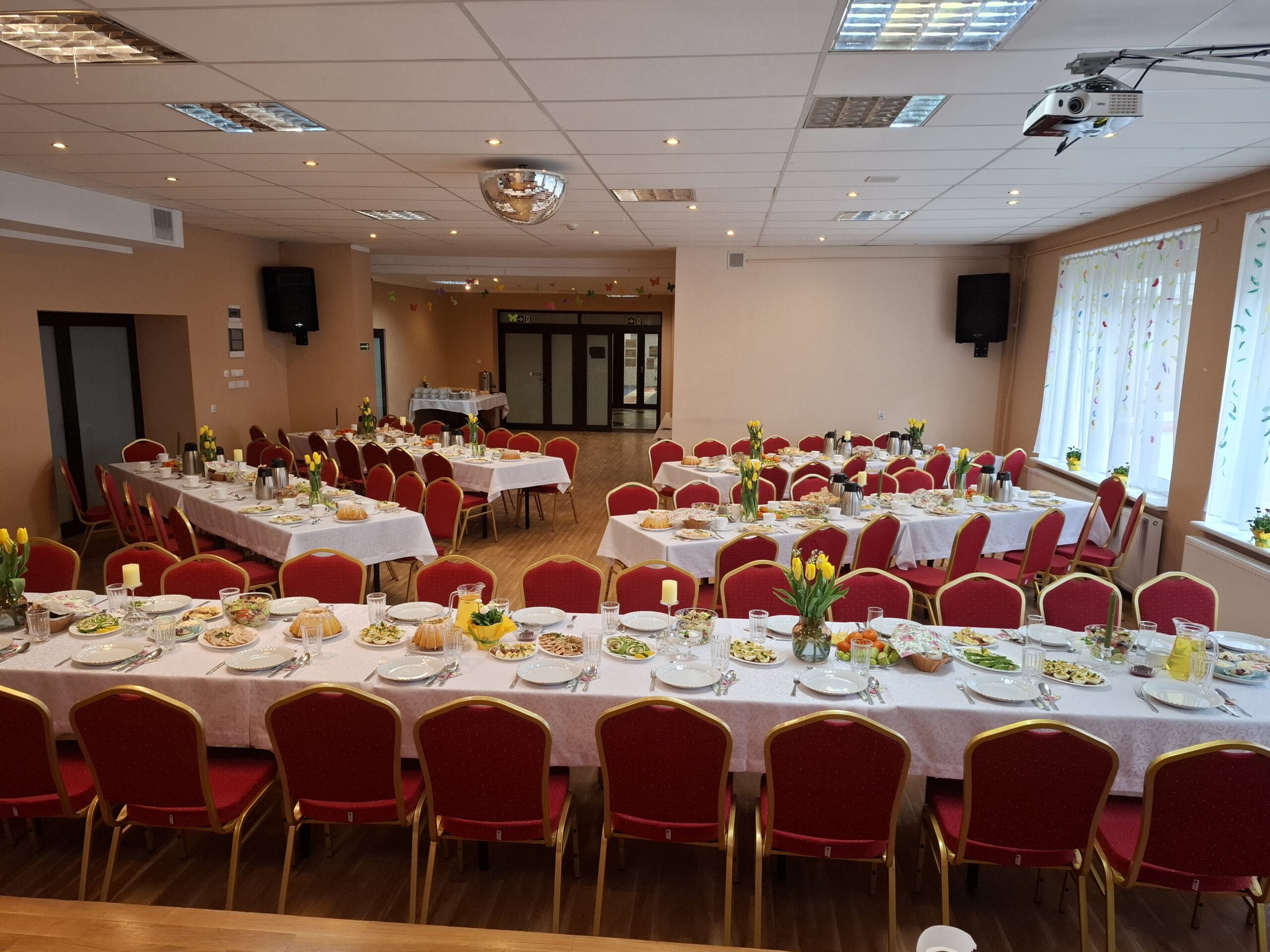 Zdjęcie świetlicy głównej. Rozstawione stoły z zastawą stołową.